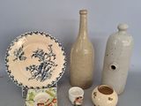 trois vases, une assiette et un vase posés sur une table