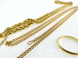 three different types of gold chains and a ring on a white surface