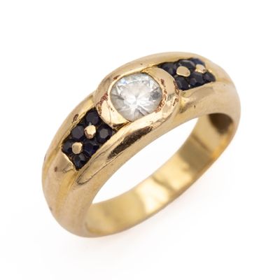 un gros plan d'une bague en or sertie d'un diamant blanc et de saphirs bleus