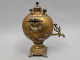 an antique brass coffee pot on a stand with a spout