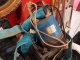 un seau bleu rempli d'outils posé sur un tas d'objets divers