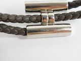 two silver metal tubes on a black leather bracelet