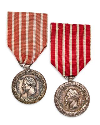 deux médailles ornées d'un ruban rouge et une médaille d'argent sur fond blanc