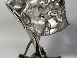 silver sculpture of a baby in a stroller on a metal stand