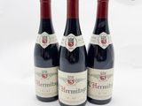 trois bouteilles de vin rouge posées l'une à côté de l'autre sur une surface blanche