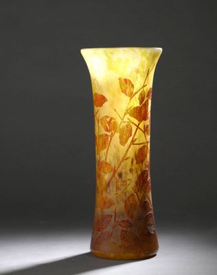 un vase orange posé sur une table blanche près d'un mur