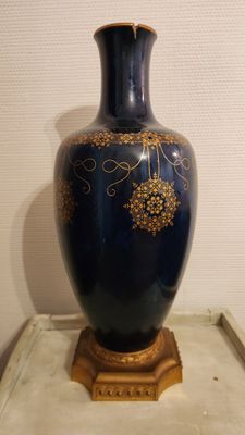 a blue vase with gold decorations on it on a table
