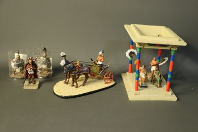 three figurines of people riding horses and a man on a horse drawn carriage