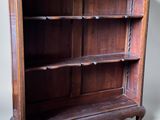 an old wooden bookcase with three shelves on wheels on a gray background