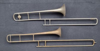 trois trombones en laiton sont alignés sur une surface noire