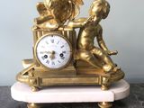 a gold clock with a statue of a boy and a rooster on it