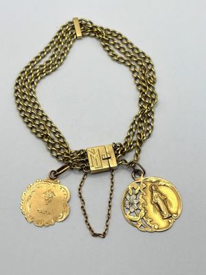 a close up of a gold necklace with two medallions on it
