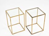 a pair of gold metal and glass side tables on a white background