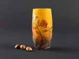a yellow vase with flowers and nuts on the table