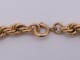 a close up of a gold bracelet on a white surface