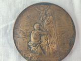a bronze medal on a white cloth with a picture of a man and a dog