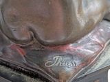 bronze statue of a man sitting on a stool with his foot resting on a pillow