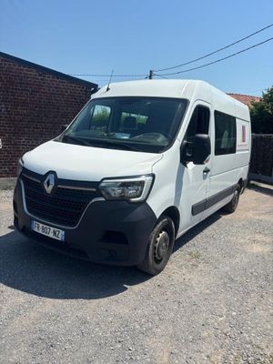 La camionnette blanche est garée sur le parking, à côté d'un mur de briques.