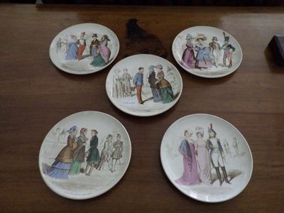 four plates with different designs on them sitting on a wooden table