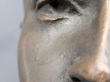 a close up of a statue of a man with silver paint on his face