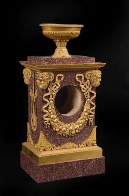 une horloge en marbre doré et rouge, surmontée d'un bol