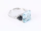 a close up of a ring with a blue topaz and black onyx