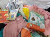 a pile of baby clothes and books on a bed