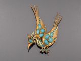 broche en forme d'oiseau plaquée or, ornée de pierres turquoise sur ses ailes