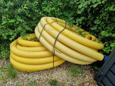 un tas de tuyaux jaunes posé à côté d'une poubelle