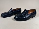 a pair of black loafers on a white surface