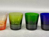 four different colored glasses lined up on a white surface