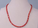 a red beaded necklace on a mannequin neck