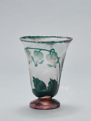 un gros plan d'un vase en verre orné de feuilles vertes