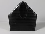 a black purse sitting on top of a table next to a white wall