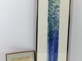 deux photos encadrées représentant des arbres et un vase bleu posés sur une table blanche