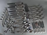 un grand nombre de cuillères et de fourchettes en argent disposées sur une table