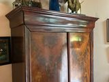 a tall wooden cabinet in the corner of a room