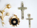 a cross, a flower, and a brooch on a white surface