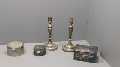 trois bougeoirs en argent et une boîte posés sur une table blanche