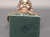 bronze statue of a man sitting on top of a green block