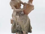 une statue représentant une femme tenant un vase sur un rocher