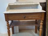 a marble sink on a wooden stand next to a refrigerator