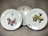 trois assiettes ornées de fleurs, posées sur une table