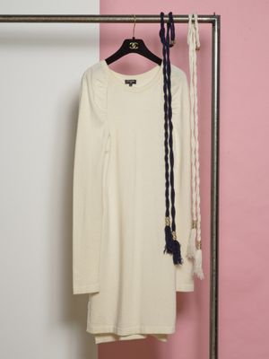 une chemise blanche suspendue à un portant, à côté d'une paire de ciseaux