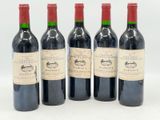quatre bouteilles de vin sont alignées sur une surface blanche