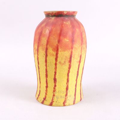 un vase jaune et rouge posé sur une surface blanche