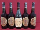 six bottles of wine are lined up on a red surface