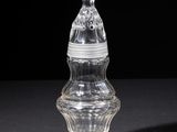 an old glass bottle with a lid on a black surface