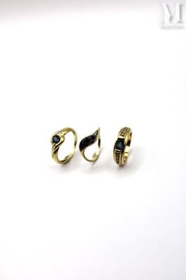 two gold rings with black stones on them on a white surface