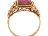 a close up of a gold ring with a red stone in it